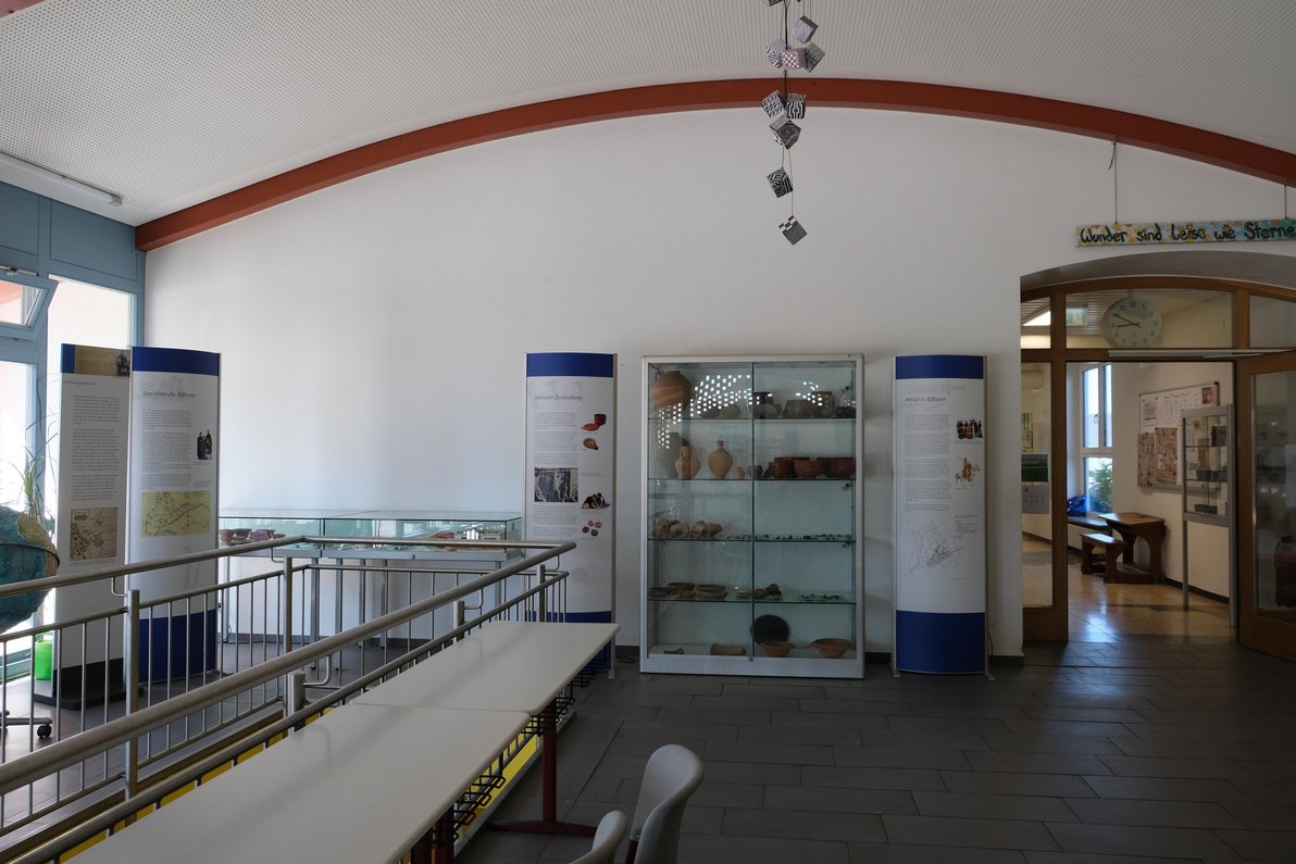 Eingangsbereich der Schule mit Vitrinen und Ausstellungsgegenständen aus der Römerzeit