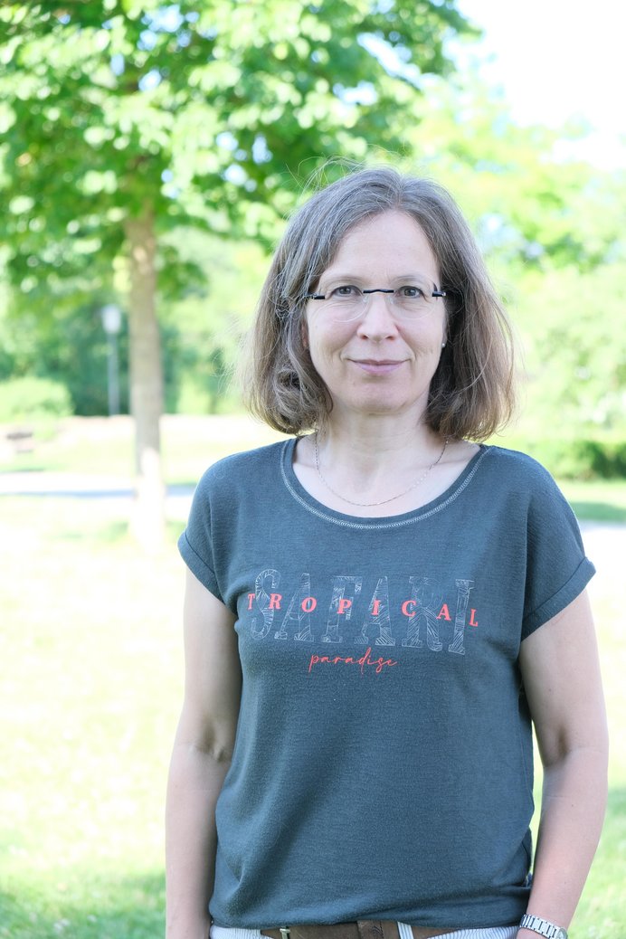 Aufnahme einer Frau vor grüner Wiese mit Baum.