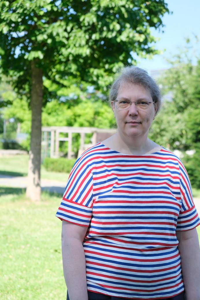 Frau mit Brille und geringeltem T-Shirt im Freien.