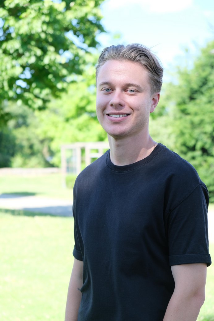 Blonder Mann im schwarzen T-Shirt im Freien.